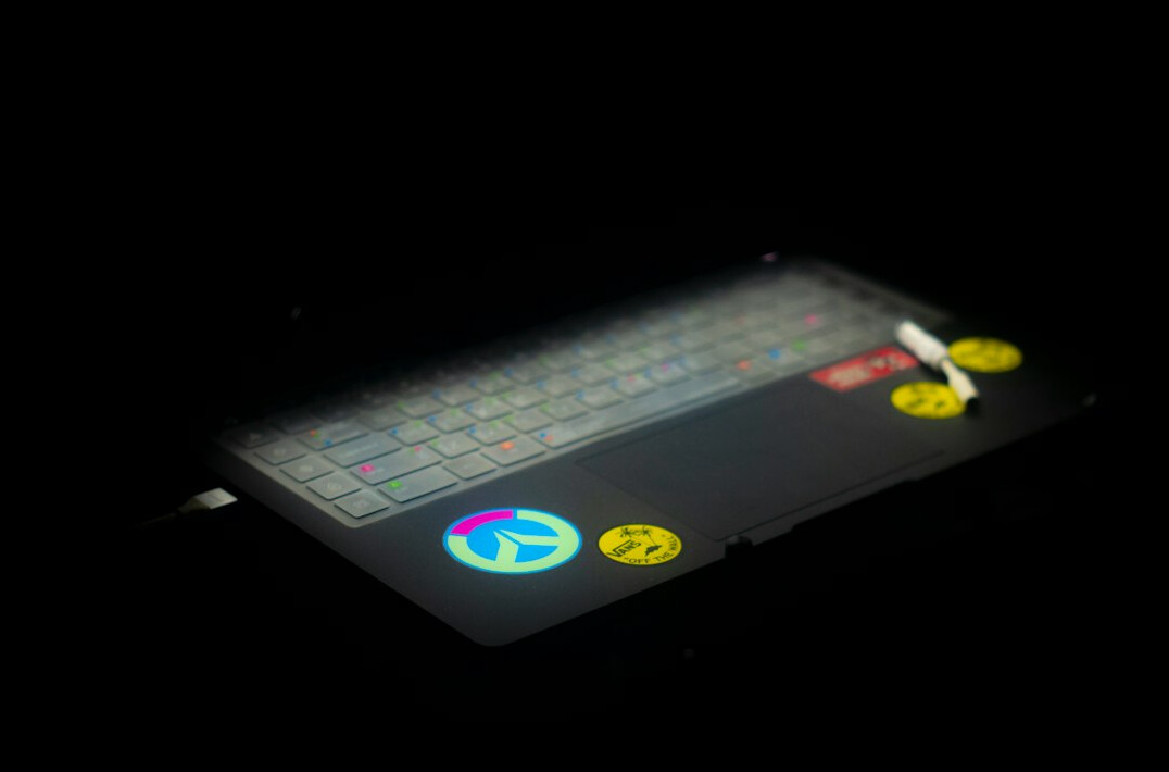 Close-up of hands typing on a laptop keyboard with code on screen